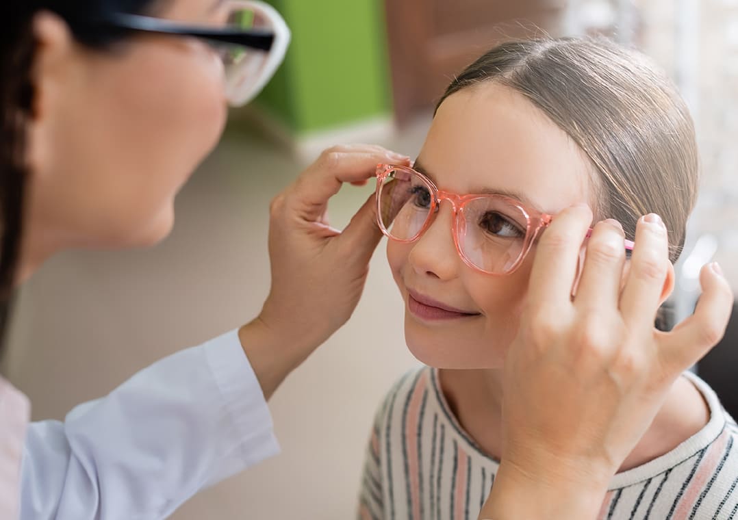 A girl being fitted with a pair of glasses